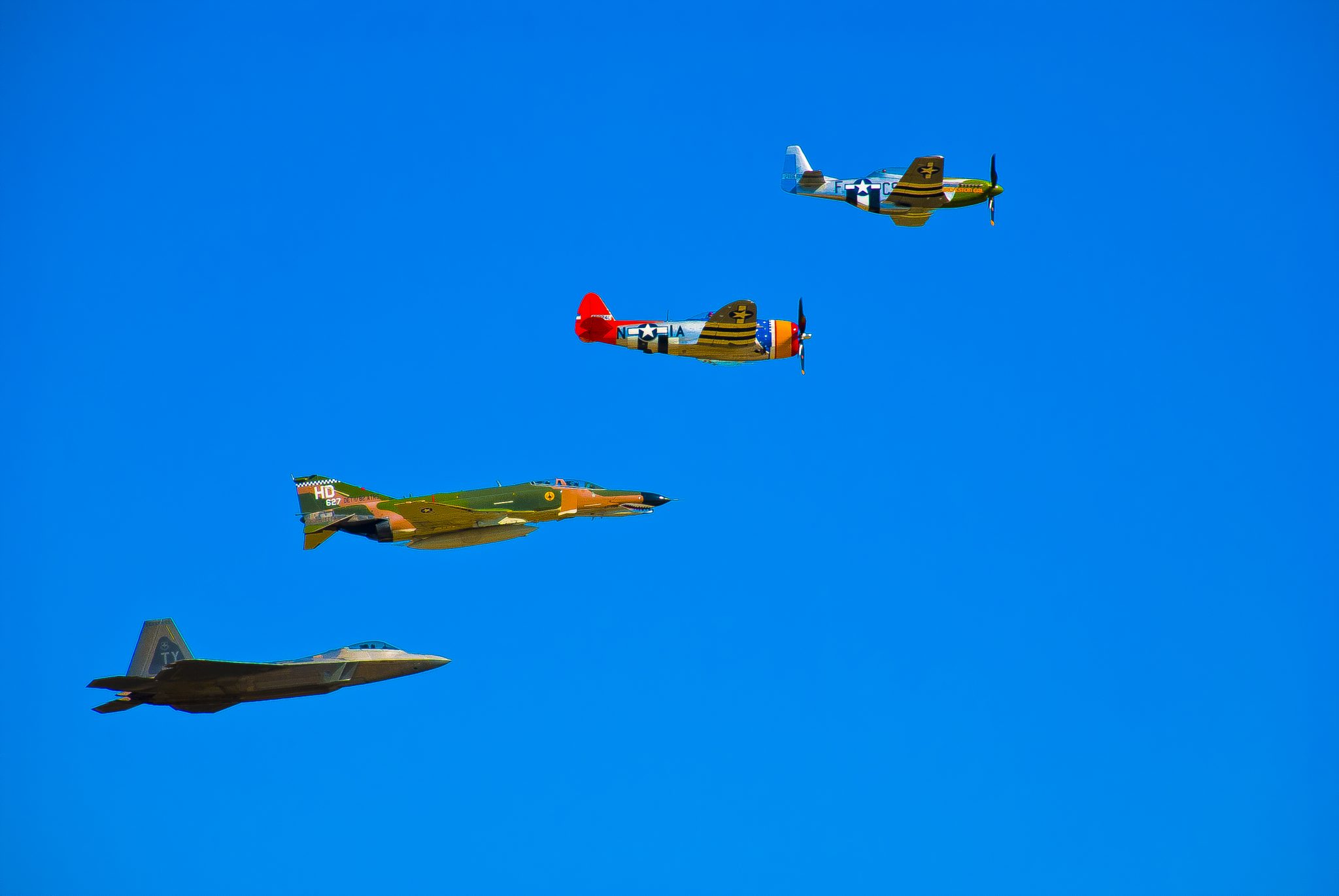 An Example of a Heritage Flight including the P-51 Mustang, P-47 Thunderbolt, the QF-4 Phatom and the F-22 Raptor (Photo: Landmark9254)