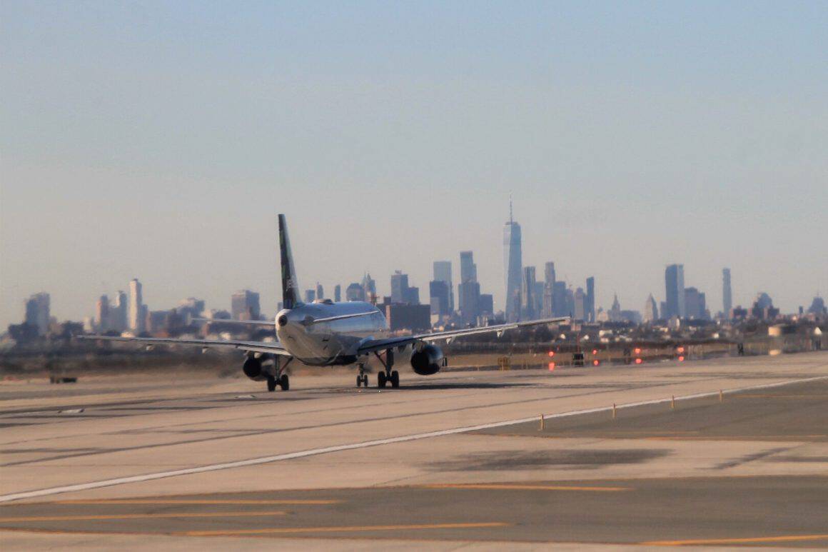 A JetBlue flight departs JFK with the Manhattan skyline in the background. 