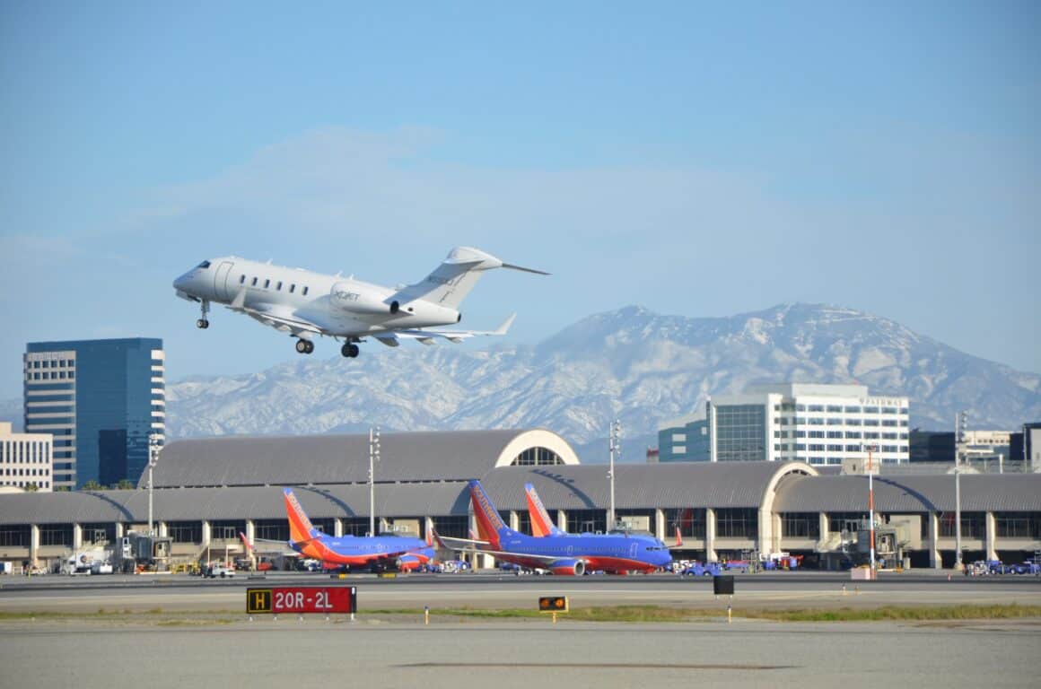 A private jet departs SNA with the terminal in the background 