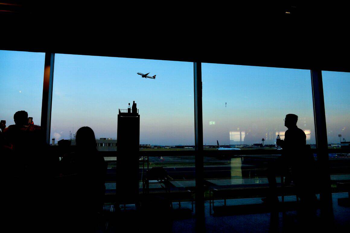 An airplane takes off outside of airport windows